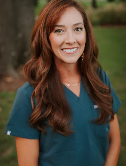 Dr. Lindsay Pauly, DDS, in teal scrubs, photographed outdoors.